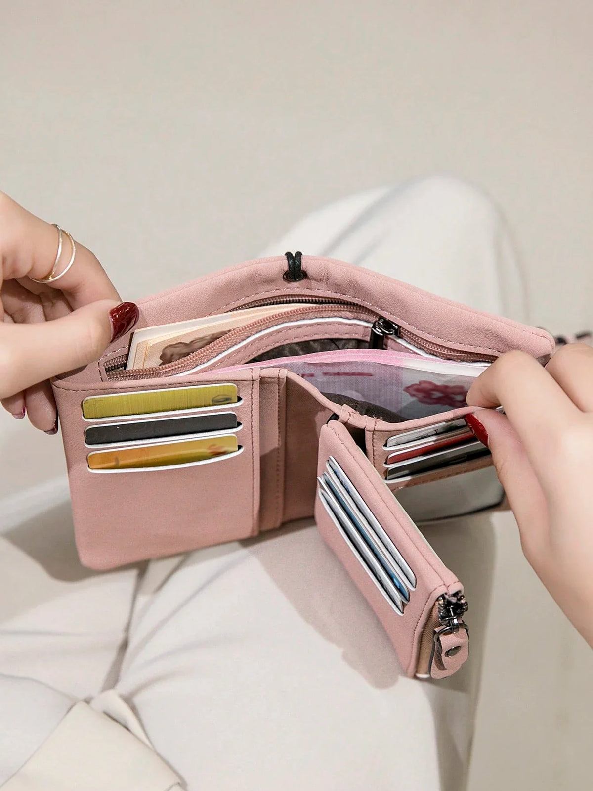 Pink tri-fold wallet opened to show card slots cash and coin storage